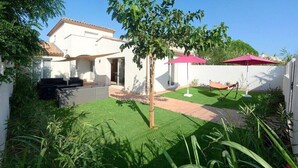 Una casa con un patio, un pequeño césped y un árbol.