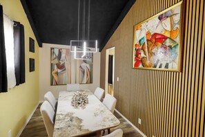 Un comedor moderno con una mesa de mármol, sillas blancas y arte contemporáneo en las paredes.