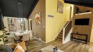 Una sala de estar moderna con sofá, mesa de comedor y escalera.
