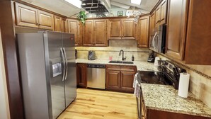 Una cocina con armarios de madera, electrodomésticos de acero inoxidable y encimera de granito.