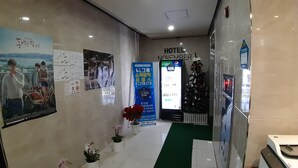 A hotel lobby with a reception desk, a Christmas tree, and various posters on the walls. - Seosan November Hotel (Seosan)