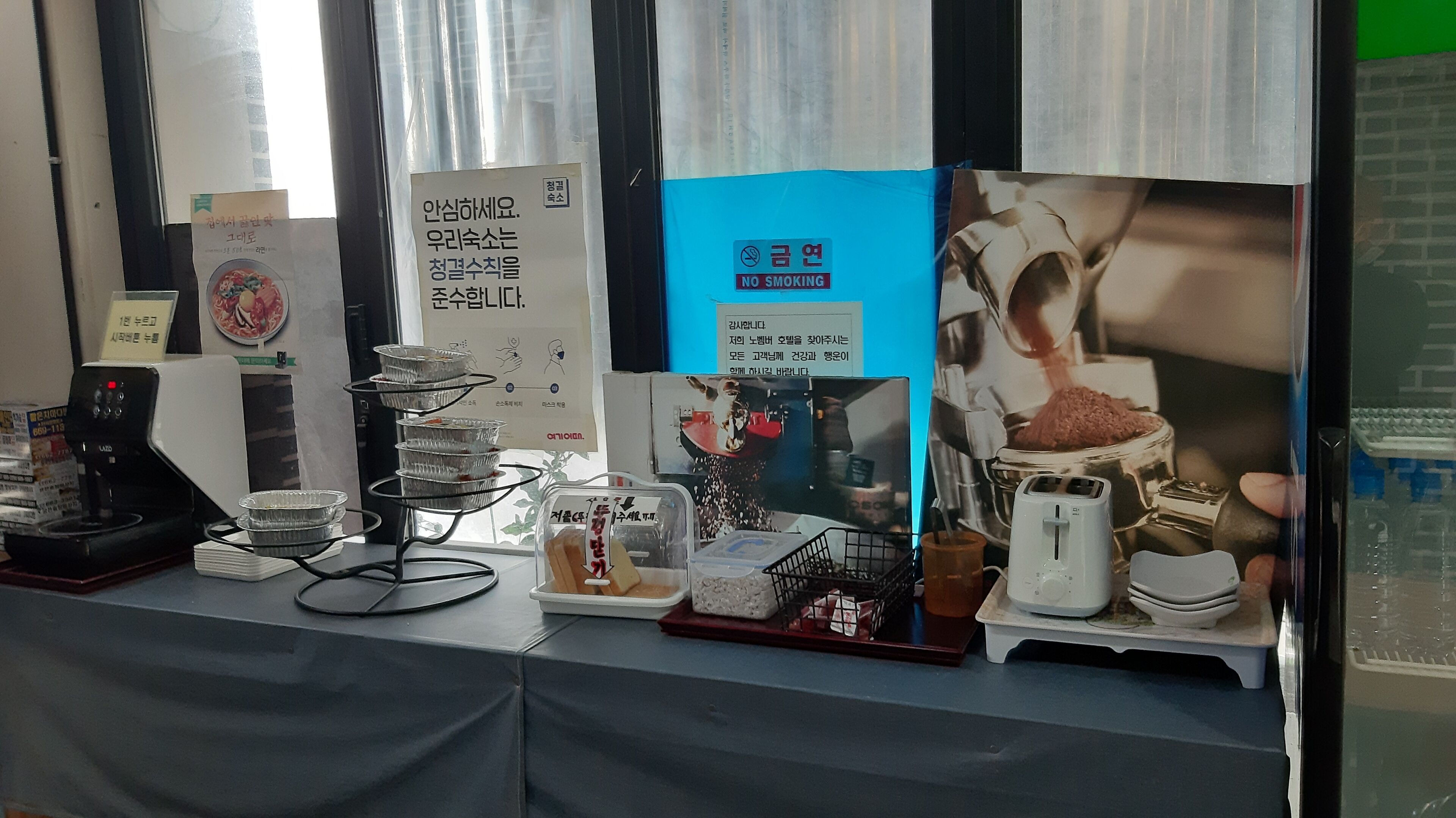 A table with various items including a coffee machine, a tray with cups, and informational posters.