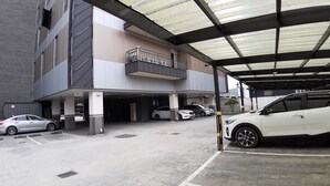 A parking garage with multiple levels and covered areas, cars parked inside, and a building with a modern design and a balcony. - Seosan November Hotel (Seosan)