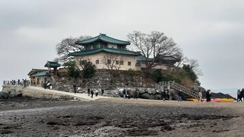 Un edificio tradicional con techo verde, paredes de piedra y una escalera de piedra que conduce hasta él.