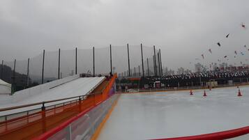 An outdoor ice rink with a clear view of the city skyline in the background.