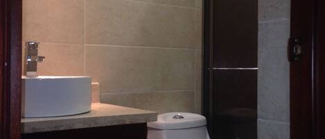 Une salle de bain avec des toilettes, un lavabo et un miroir.
