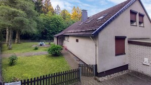 A single-story house with a sloped roof, a small porch, and a fenced yard. - Nice apartment in Goslar OT Hahnenklee with WiFi (Goslar OT Hahnenklee)