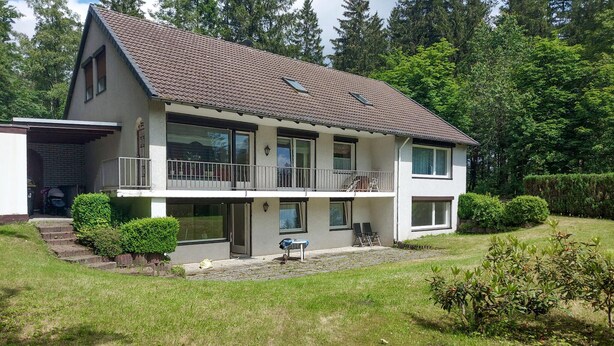 A two-story house with a balcony, a garage, and a well-maintained lawn. - Nice apartment in Goslar OT Hahnenklee with WiFi (Goslar OT Hahnenklee)