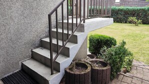A concrete staircase with metal railings leading to a door, surrounded by a garden with hedges and a brick pathway. - Nice apartment in Goslar OT Hahnenklee with WiFi (Goslar OT Hahnenklee)