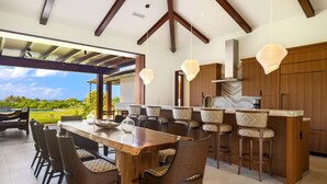 A modern kitchen with a large island, bar stools, and wooden cabinetry. - Hale Kipu by Alekona Kauai: Luxury 5br Ocean View Home w Pool, Fire pit, Spa (Koloa)