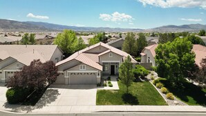 A suburban neighborhood with single-family homes, well-maintained lawns, and a clear view of distant mountains. - NEW Roomy Upscale, Mt. Rose Ski/Tahoe 25-Min, XL Sofa and 2 Work Desks  (Reno)