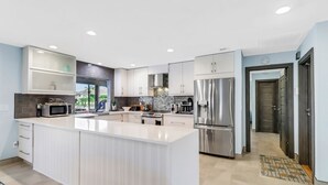 Une cuisine moderne avec des meubles blancs, des appareils en acier inoxydable et un grand îlot central.
