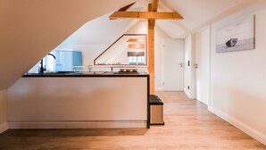 Una cocina moderna con una isla central, vigas de madera y vista al área de estar.