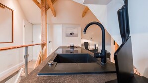 Una cocina moderna con una isla central, grifo negro y vigas de madera.