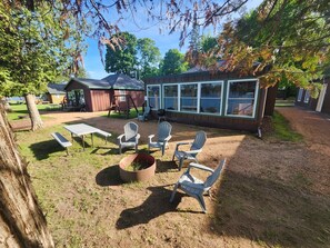 A backyard with a barbecue area, picnic tables, and outdoor seating.