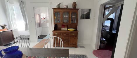 Un comedor con un aparador de madera, una mesa con camino de mesa floral y un jarrón azul.