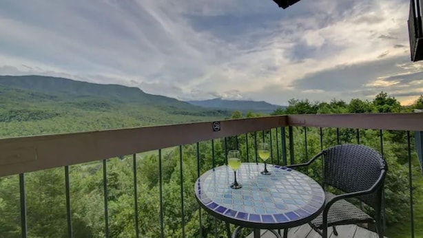 A balcony with a round table and two chairs, overlooking a mountainous landscape. - Beautiful views! Sleeps 2, Indoor Pool (Gatlinburg)