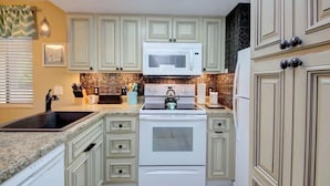 A kitchen with light green cabinets, a white stove, a microwave, and a sink. - Beautiful views! Sleeps 2, Indoor Pool (Gatlinburg)