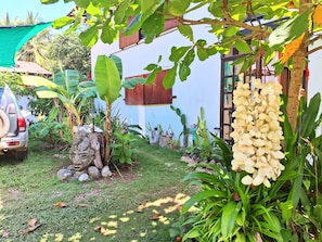 Um jardim com diversas plantas, uma escultura de pedra e um carro estacionado.