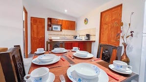 A dining area with a table set for six, wooden cabinets, a microwave, and a refrigerator. - Villa Banano 09, Near to the beach with Pool (Jacó)