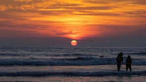 A sunset over the ocean with people standing on the shore. - Villa Banano 09, Near to the beach with Pool (Jacó)