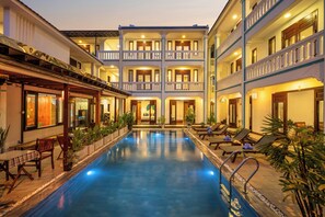 A hotel with a central pool, multiple balconies, and outdoor seating areas.