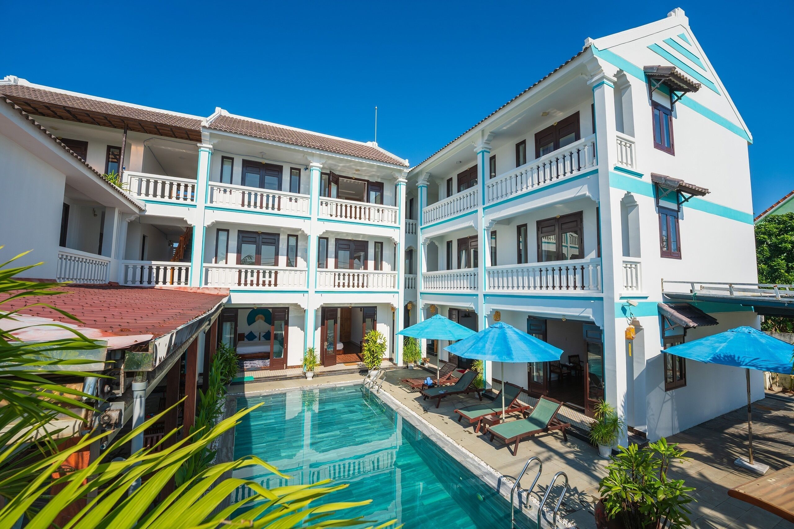 A hotel with a swimming pool, multiple balconies, and outdoor seating areas.