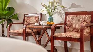 A wooden dining table with two chairs, a vase with white flowers, and a plate of lemons.