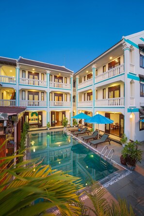 A multi-story hotel with a central pool area, balconies, and outdoor seating.