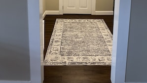 Un pasillo con una puerta blanca, un tapete estampado y una lámpara colgante.