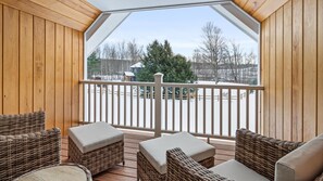 A wooden deck with wicker furniture and a view of a snowy landscape.