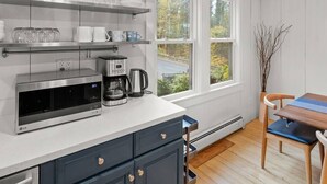 Une cuisine moderne équipée d’un four à micro-ondes encastré, d’une machine à café et de verres disposés sur des étagères.