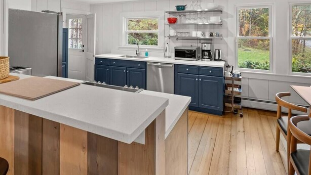 Une cuisine moderne dotée d’un îlot central, d’appareils électroménagers intégrés et offrant une vue sur l’extérieur.