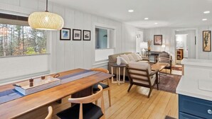 Une cuisine moderne avec des meubles en bois, un coin repas avec une table et des chaises en bois, et un coin salon confortable avec un canapé et des fauteuils.
