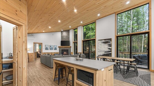 Una cocina moderna con una isla central, suelo de madera, ventanas amplias y una chimenea.