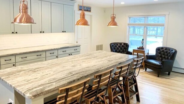 A modern kitchen with a large island, wooden chairs, and pendant lighting. - Expansive Stowe home, amazing location and hot tub (Stowe)
