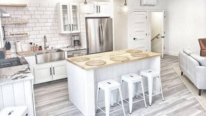 Una cucina moderna con mobili bianchi, un frigorifero in acciaio inossidabile e un'isola centrale con sgabelli.