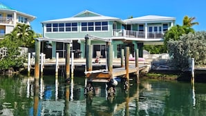 A waterfront house with a dock extending into the water, featuring multiple levels and balconies.