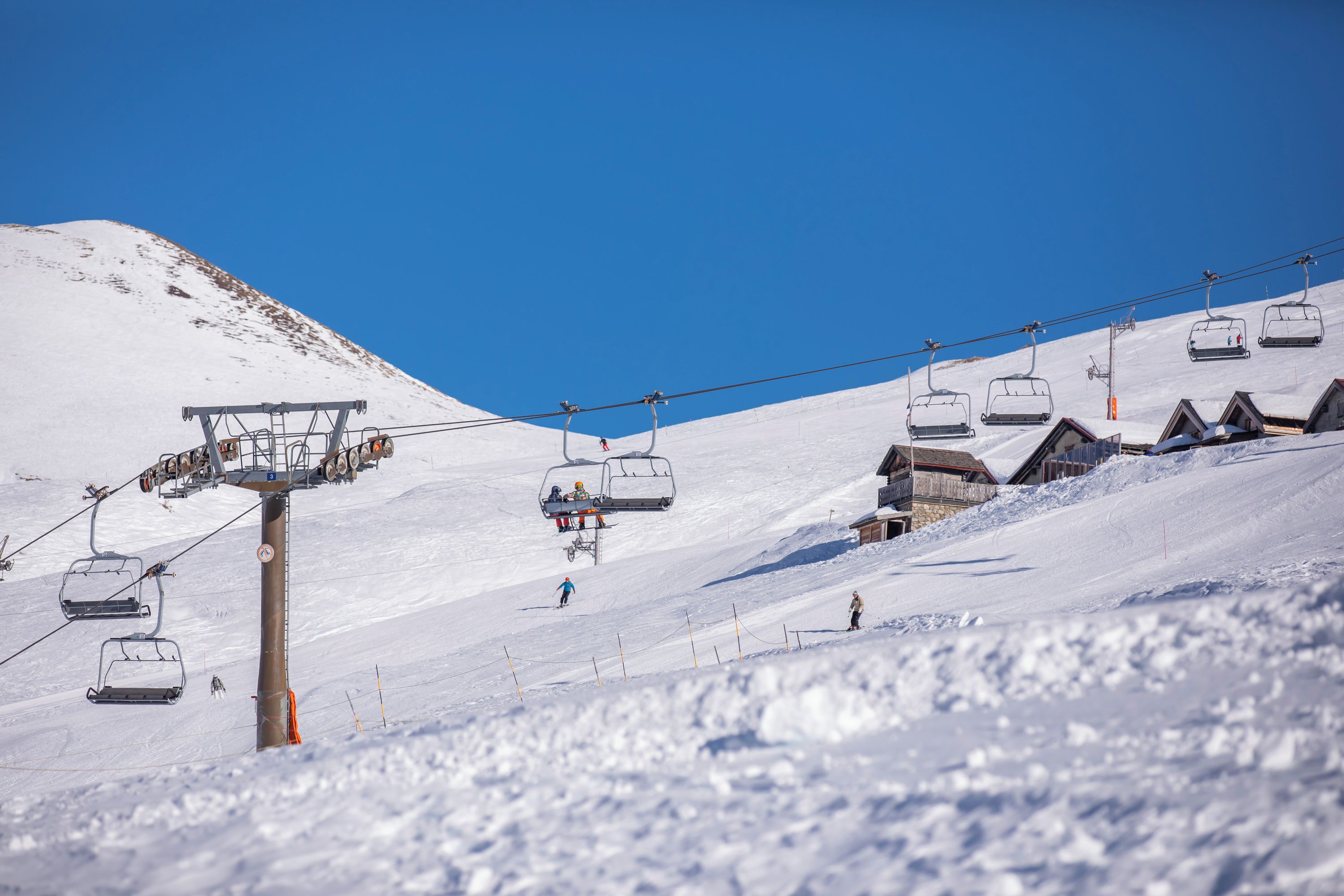 Una seggiovia con cabine che salgono lungo un pendio innevato.