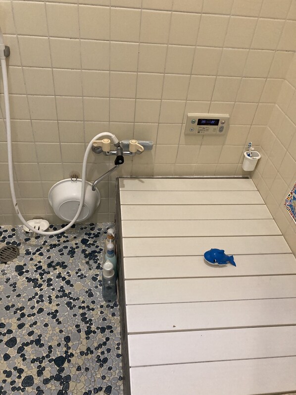 A bathroom with a white toilet, a bidet, a digital clock, and a small blue fish toy on the floor.
