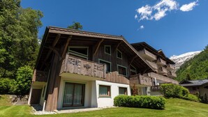Eine Holzchalet mit Balkonen, großen Fenstern und einem Berg im Hintergrund.