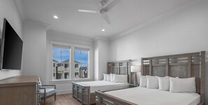 Une chambre d’hôtel moderne, dotée de deux lits, d’un bureau et d’une grande fenêtre donnant sur d’autres immeubles.