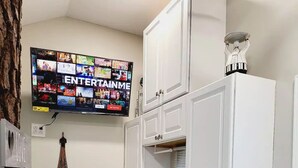 Une cuisine compacte avec des meubles blancs, un plan de travail en granit, un four à micro-ondes encastré, un évier et une petite cuisinière.