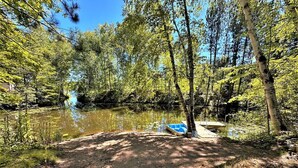 Ein Campingplatz mit einem Feldweg, der zu einem Steg über einem stillen See führt, umgeben von dichtem Baumbestand.