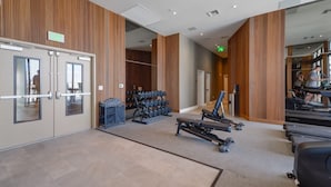 Et fitnessrum med træningsudstyr, et løbebånd og et spejl.
