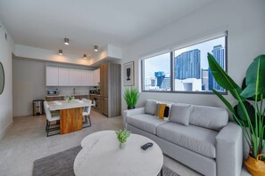 A modern apartment with a dining area, kitchen, and a large window with a city view. - Modern 1BR • Pool • 30min to Miami Stadium (Miami)