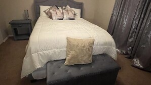 Ein Schlafzimmer mit einem Bett, einem Nachttisch, einer Bank und einem Vorhang.