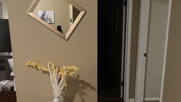 Ein Flur mit einem runden Tisch, einem Spiegel und einer Vase mit Blumen.