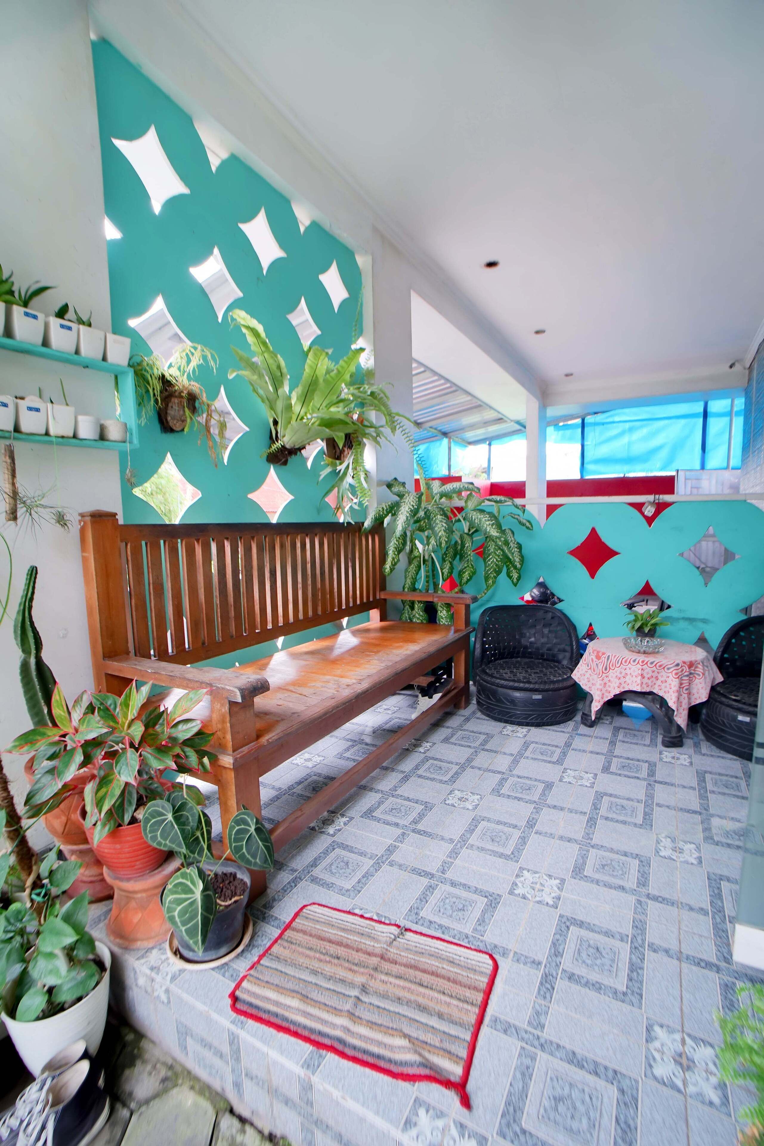 A room with a wooden bench, potted plants, a patterned floor, and a wall with geometric designs.