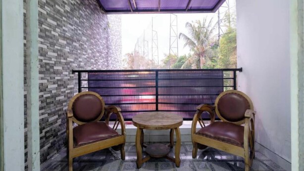Un balcon avec un mur décoré de motifs, deux chaises en bois et une petite table.